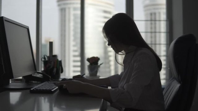 attractive girl working in the office. silhouette of a business woman on the background of a large window