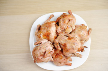 Six baked cornish hens on white plate top view
