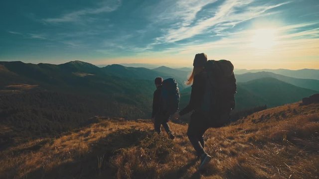 The man and woman walking in the mountain on the sunset background. slow motion