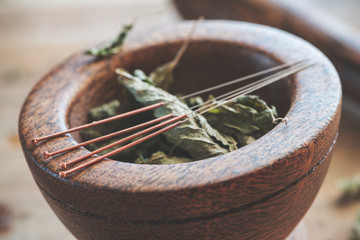 Akupunktur Nadeln auf einem Holzmörser mit grünen Teeblättern