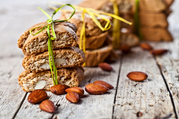 Fresh Italian cookies cantuccini stackes and almond seeds on ructic wooden table background.
