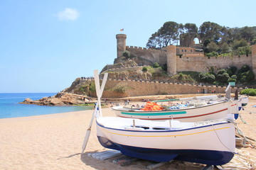 Traditional fishing boats on the beach of Tossa de Mar, a charming historic town constructed around...