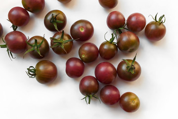 small brown cherry tomatoes on the white table, view from above.