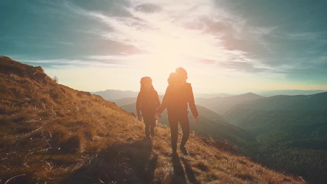 The couple walking in mountains against the sunset background. slow motion