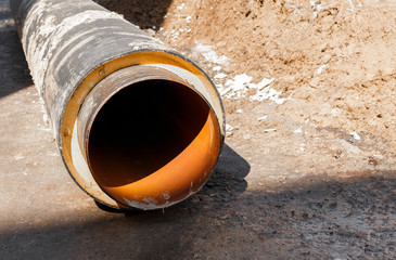 a large orange pipe lies in the mud on the construction site close-up shot