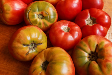 the background of beautiful and vibrant tomatoes from the home garden with natural cracks. homemade tomatoes spread out on the table. Tomatoes view from above background. .