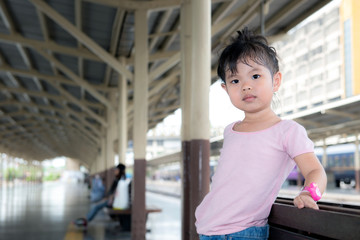 Cutie little asian girl pose and look at camera with vintage railway in background.