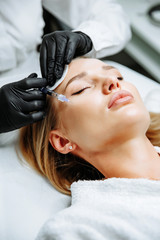Young woman receiving plastic surgery injection on her face