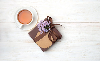 lilac flower, gift box and cup of tea on white background. concept birthday, gift for dad, men, brutal style. holiday spring greeting background. top view, copy space