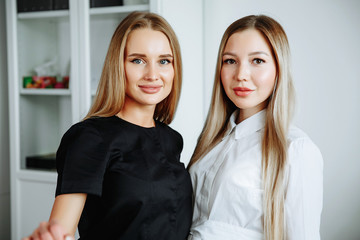 Two successful confident beauty salon female owners looking at camera. Cheerful female beautician is working with cosmetology. Two women crossed arms with confidence.