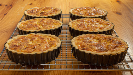 Six quiche on cooling rack on pine table