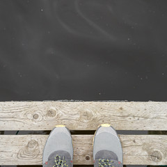 Closeup of the feet on the edge of the pier against the background of water. River, lake or...