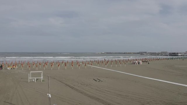 Aerial view of the coast of Anzio, a small sea town near Rome, in Italy. There is no one on the beach on this cold spring day. The blue sea with its waves is rough. In the sky there are some clouds.