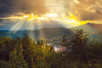 Obraz na płótnie Canvas Sun rays beams over rural mountain resort epic landscape
