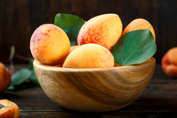 Delicious ripe apricots in a wooden bowl on the table close-up.