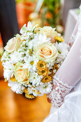 hand of the bride in a white glove with a bridal bouquet of daisies and delicate pink roses