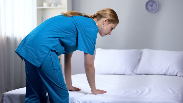Young Nurse Preparing Clean Bed-linen In Rehabilitation Center, Good Service