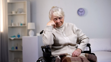 Depressed aged lady in wheelchair thinking about health problems at hospital
