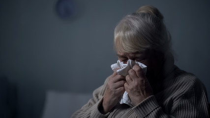 Desperate elderly female deeply crying in dark room, hospice loneliness, problem