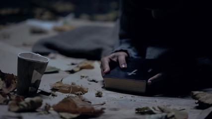 Miserable vagabond holding bible and praying to God, strong belief, faith