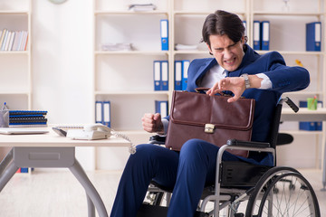 Young male employee in wheelchair working in the office 