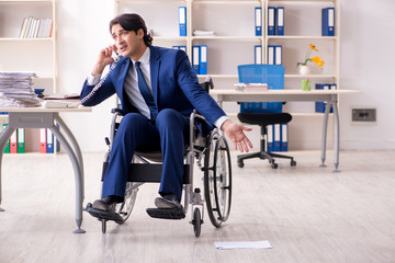 Young male employee in wheelchair working in the office 