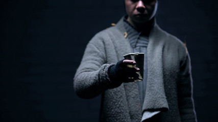 Homeless person holding old paper cup asking for money on street, person in need