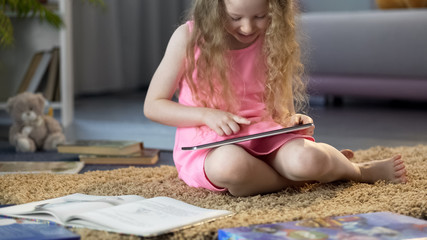 Smiling child watching educational video on tablet, using modern technology