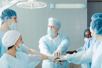 united friendly surgeons putting hands together on the top of each other. close up photo.