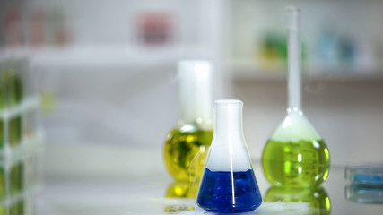Sample of blue substance in flask standing on table of laboratory, washing agent
