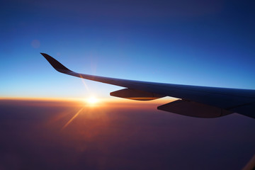Fototapeta na wymiar red sunlight spreading on aerial cloud and land below airplane wing