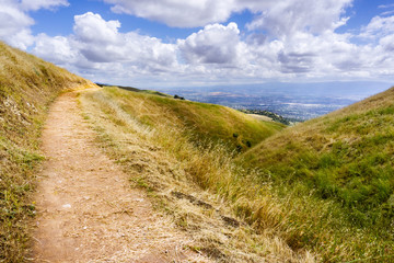 Fototapeta premium Hiking trail through the hills of south San Francisco bay area, San Jose visible in the background, California