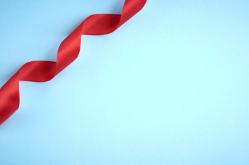 Red ribbon on blue background composition, flat lay