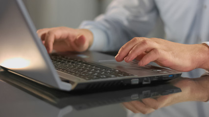 Male hands typing on laptop, company employee working office, information search