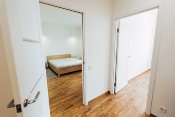 modern light interior. room with white walls and wooden floor. white open door.