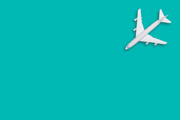 Flat lay travel concept design with plane on tiffany background with copy space. White blank model of a passenger plane.