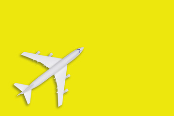 Flat lay travel concept design lay with plane on yellow background with copy space. White blank model of a passenger plane. 