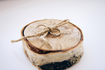 wedding rings. jewelery in white and yellow gold. Wedding ring on the wooden texture. wooden stub