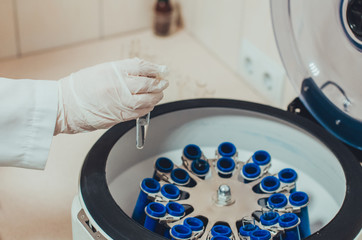 Doctor holding a sample and a medical centrifuge at the blurred background in a laboratory. Concept...