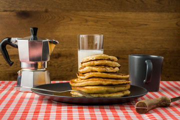 Delicious pancakes with milk and coffee for breakfast on the background of a beautiful tablecloth.