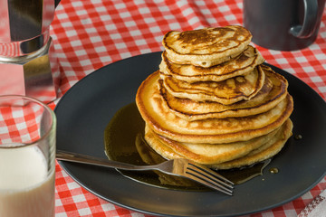 Delicious pancakes with milk and coffee for breakfast on the background of a beautiful tablecloth.