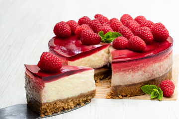 Homemade cheesecake with raspberry jelly on white wooden table