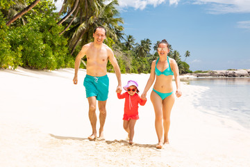 Smiling Young Family Walking On The Beach