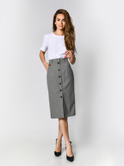 Young beautiful woman posing in new white bluesque and gray skirt on high heels full body on a...