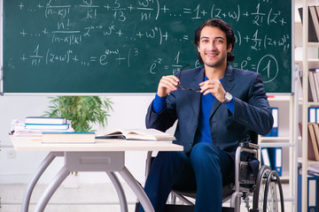 Young handsome man in wheelchair in front of chalkboard 