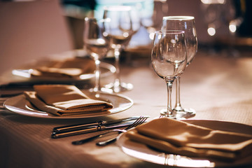 served table with white tablecloth. white plates, wine glass, fork, knife