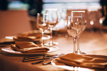 served table with white tablecloth. white plates, wine glass, fork, knife