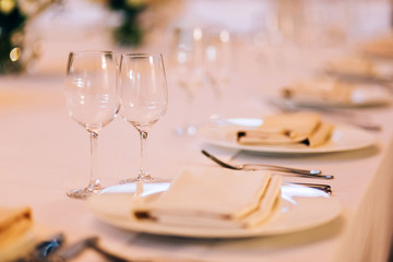 served table with white tablecloth. white plates, wine glass, fork, knife