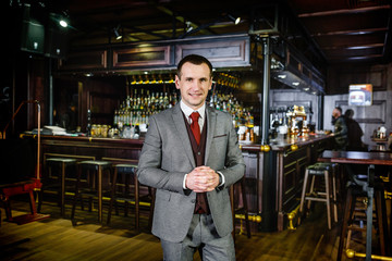 Cheerful man in a suit with a cigar is resting in the pub in the evening after work