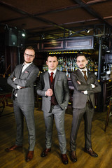 Three successful stylish businessmen in a pub. Three business partners in classic suits in a nightclub